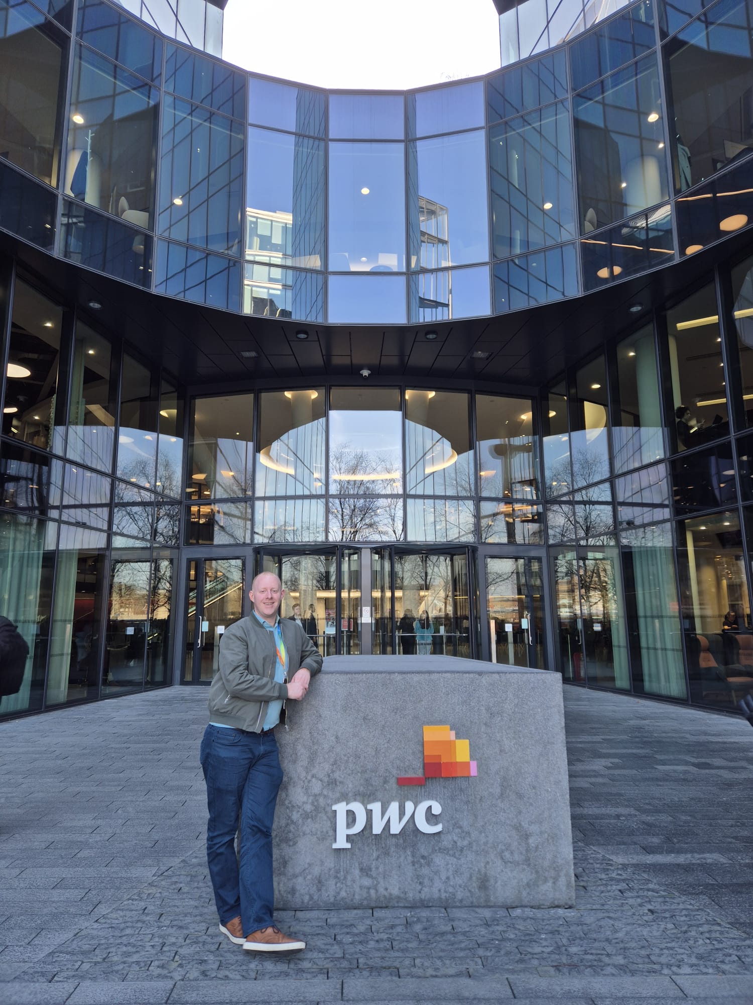 Tony McBride standing beside the PwC sign outside the PwC office in London, where he worked in workforce planning
